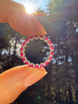 Person holding a circular object with pink stones against a blurred natural background